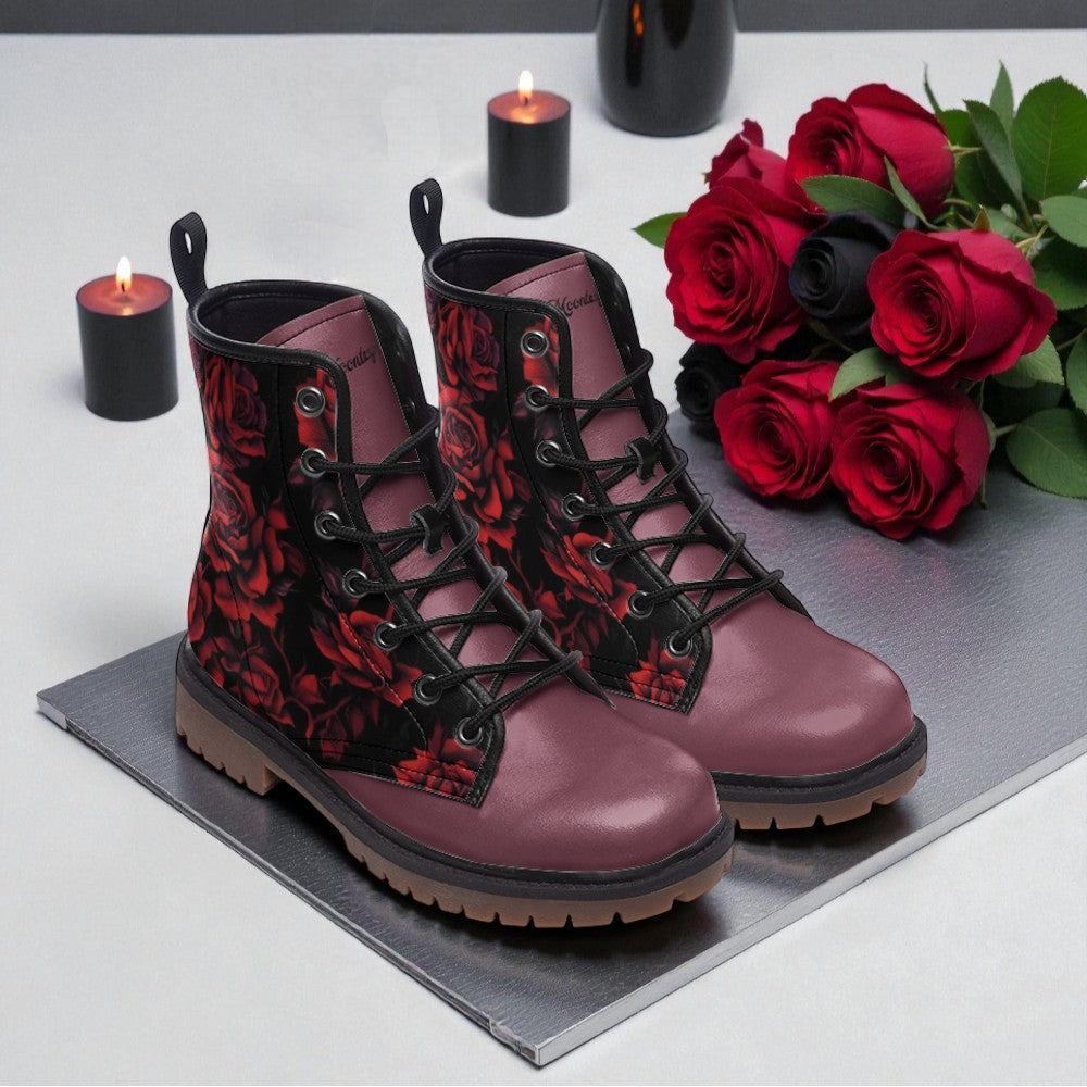 A pair of red floral boots sits on a gray surface, accompanied by a bouquet of red roses and two lit candles.