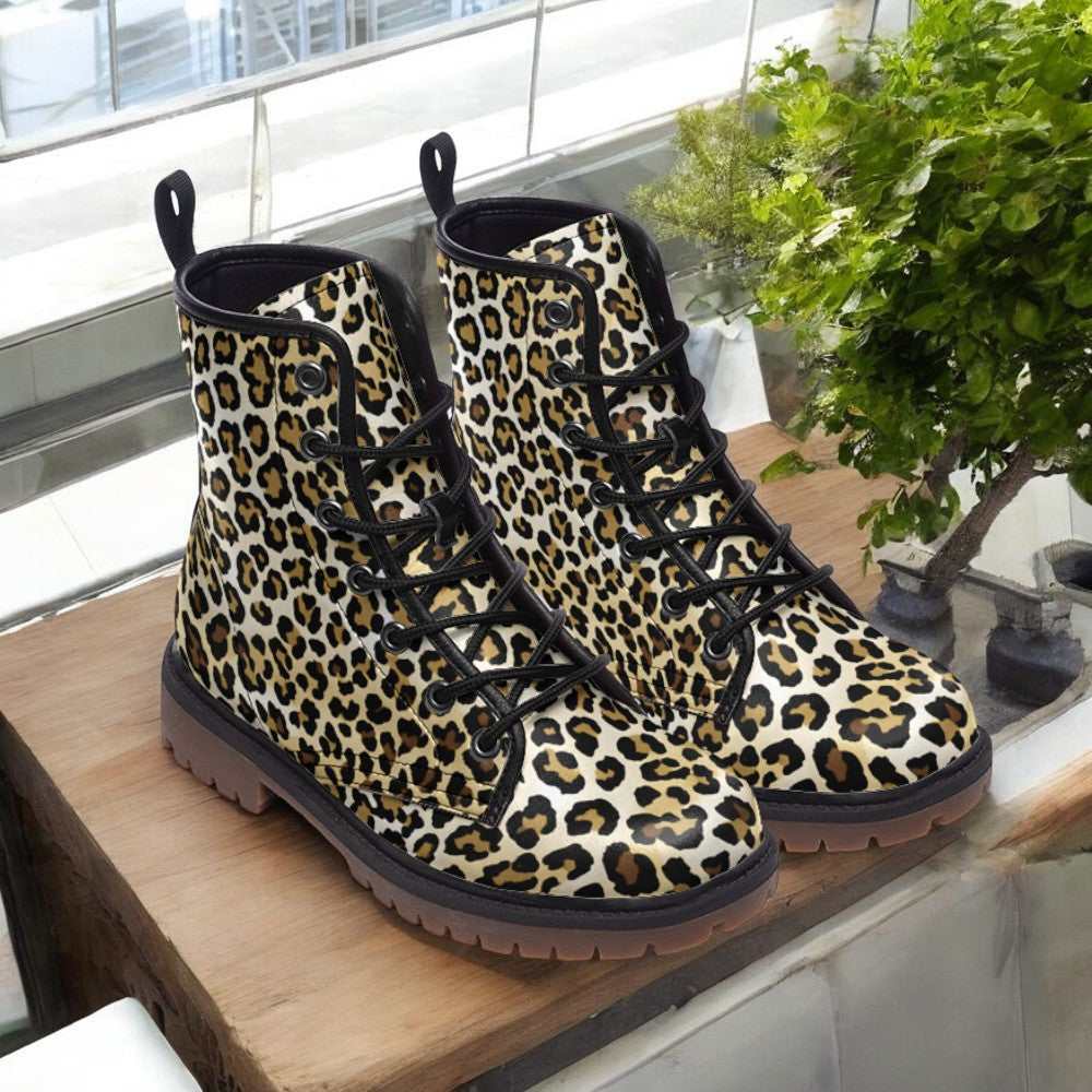 A pair of leopard print boots is displayed on a wooden surface, with a potted plant visible in the background.