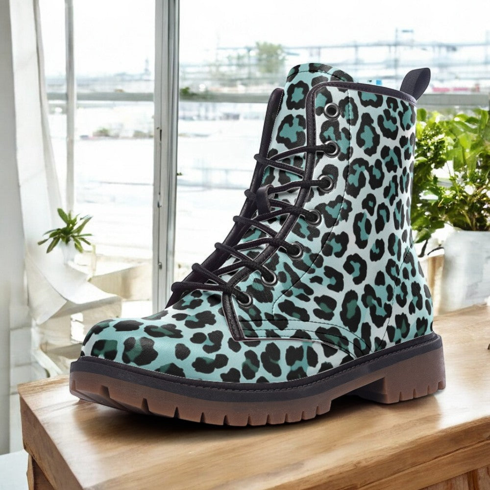 A leopard print boot is displayed on a wooden surface, with a window and plants visible in the background.