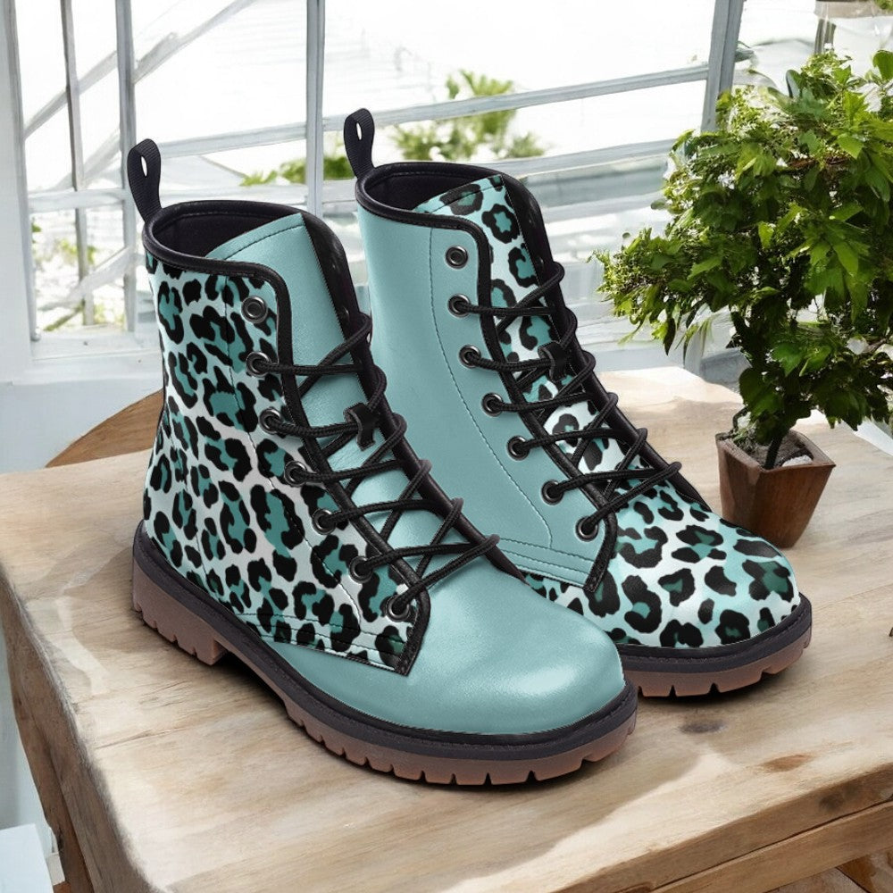A pair of blue and white leopard print boots with black laces, placed on a wooden surface near a potted plant.