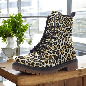 A leopard print boot is displayed on a wooden surface, with a potted plant visible in the background.