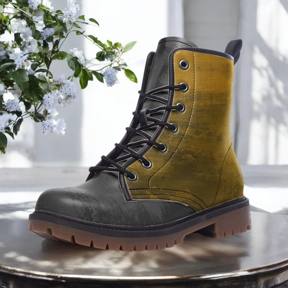 A pair of tan and black boots with a lace-up design, placed on a wooden surface against a backdrop of white flowers.