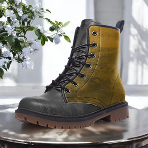 A pair of tan and black boots with a lace-up design, placed on a wooden surface against a backdrop of white flowers.