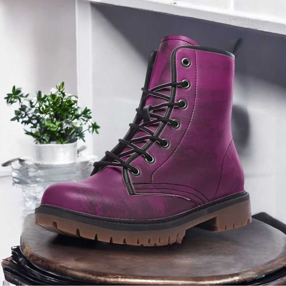 A purple lace-up boot is displayed on a wooden surface, with a small potted plant in the background.