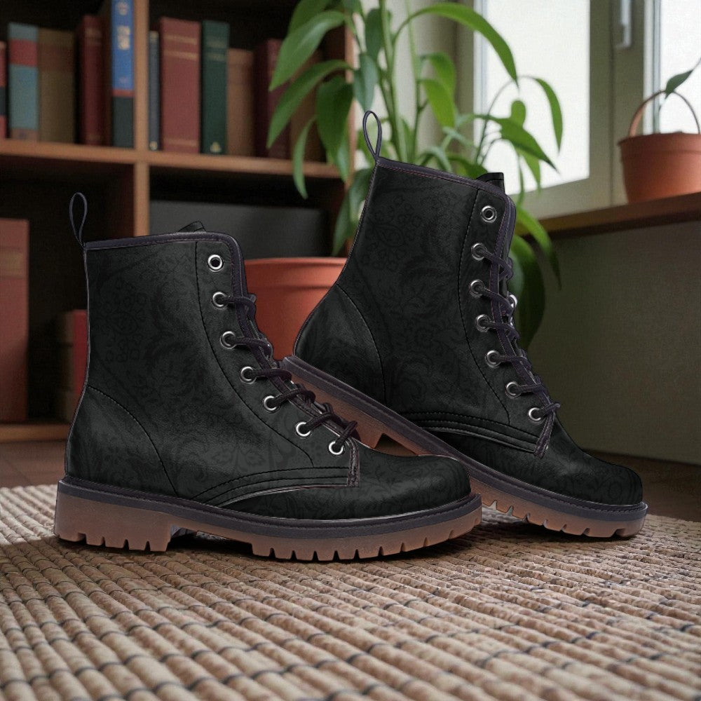 A pair of black boots with a floral pattern, placed on a woven rug in front of a bookshelf.