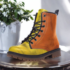 A yellow and orange boot is displayed on a round table, with a potted plant to the left and a white vase to the right.