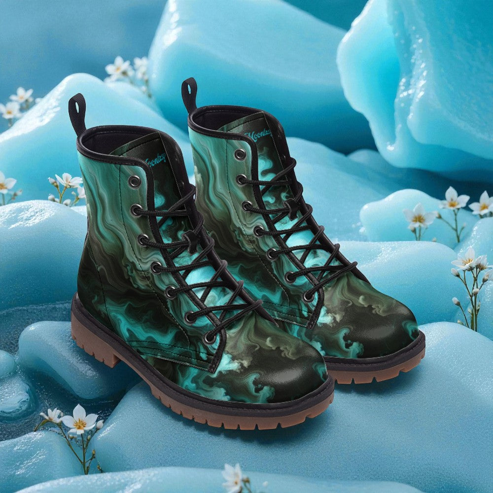 A pair of green and black patterned boots with black laces, placed on a surface with small white flowers.