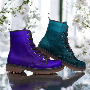 A pair of purple and teal combat boots are displayed against a backdrop of white flowers.