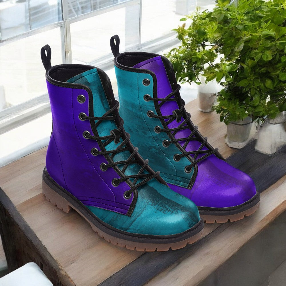 A pair of colorful boots with purple and teal laces, placed on a wooden surface next to a potted plant.