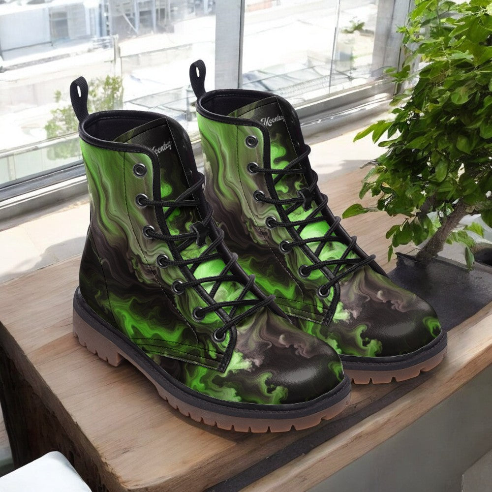A pair of green and black patterned boots with a distinctive design, placed on a wooden surface near a window.