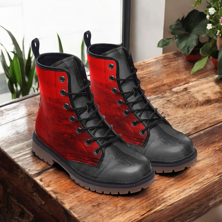 A pair of red and black combat boots are displayed on a wooden surface, with a window and potted plants in the background.
