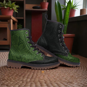 A pair of green patterned boots with black laces and soles, placed on a woven mat in a room with potted plants.
