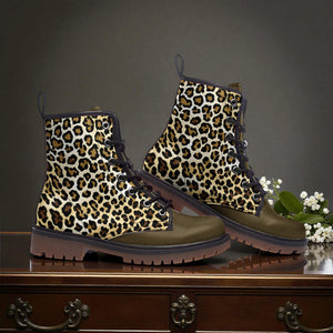 A pair of leopard print boots is displayed on a wooden surface, with a small bouquet of white flowers to the side.
