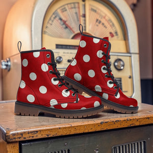A pair of red and white polka dot boots are displayed on a wooden surface in front of a vintage radio.