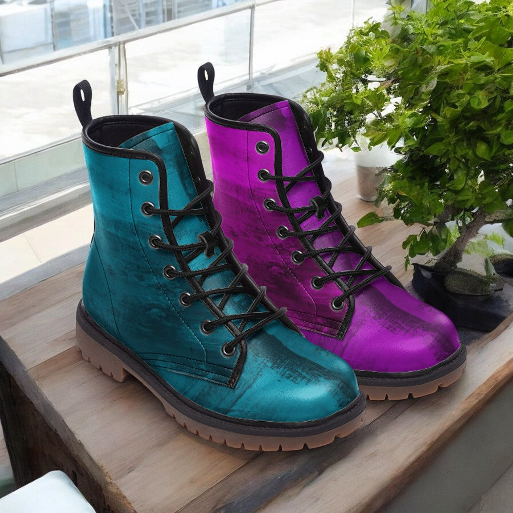 A pair of colorful boots, one in blue and the other in purple, are displayed on a wooden surface next to a potted plant.