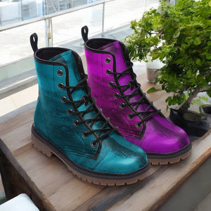 A pair of colorful boots, one in blue and the other in purple, are displayed on a wooden surface next to a potted plant.