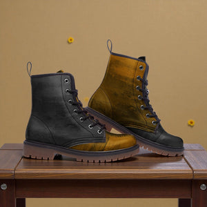 A pair of black and gold boots are displayed on a wooden table against a beige background.
