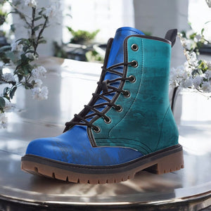 A blue and green boot with a lace-up design is displayed on a table, surrounded by white flowers.