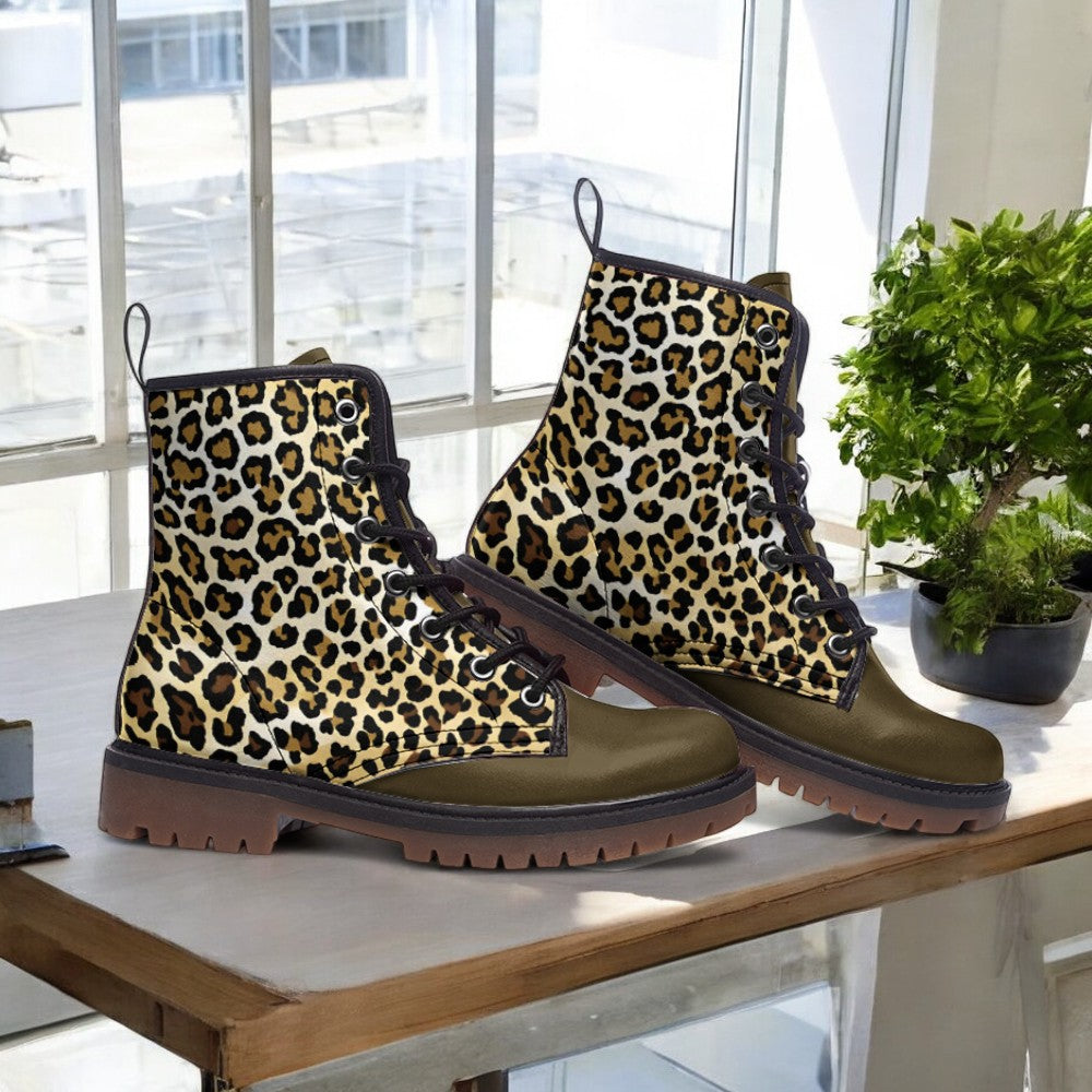 A pair of leopard print boots sits on a wooden surface, with a potted plant visible in the background.