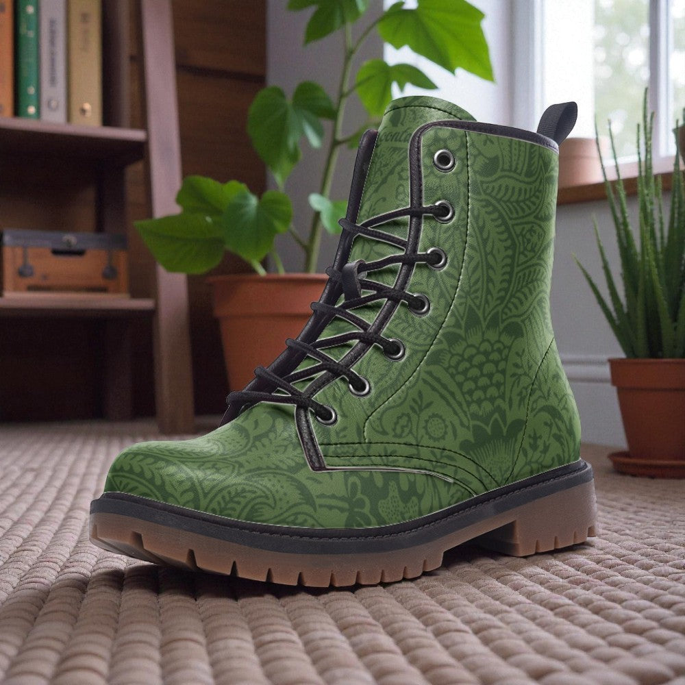 A pair of green patterned boots sits on a textured surface, with potted plants and a bookshelf in the background.