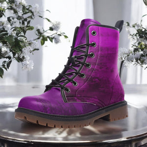 A purple, textured, and patterned boot is displayed on a round metal surface, with white flowers visible in the background.