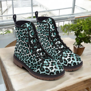 A pair of leopard print boots is displayed on a wooden surface, with a potted plant visible in the background.