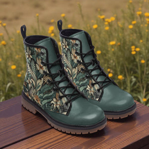 A pair of green floral patterned boots sits on a wooden surface, with a field of yellow flowers in the background.