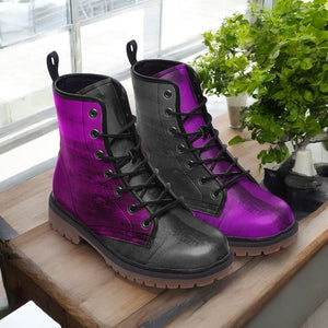 A pair of purple and black combat boots are displayed on a wooden surface, with a potted plant visible in the background.