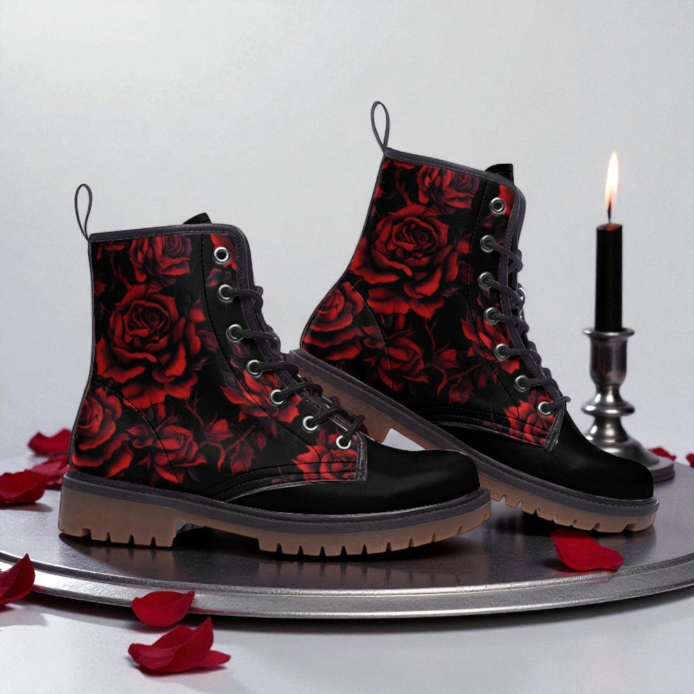 A pair of black boots with red rose patterns, placed on a silver tray with rose petals scattered around.