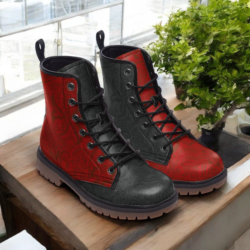 A pair of red and black combat boots are displayed on a wooden surface, with a potted plant visible in the background.