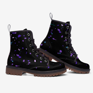 A pair of black boots with purple splatter designs on them.