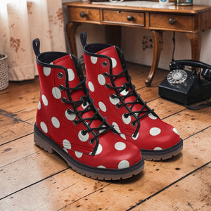 A pair of red boots with white polka dots is placed on a wooden floor, with a black telephone and a wooden dresser in the background.