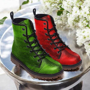 A pair of green and red combat boots are displayed on a silver table, with white flowers in the background.